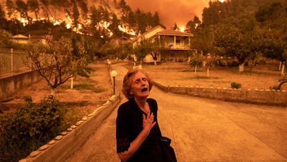 A woman as wildfire approaches her home in Greece