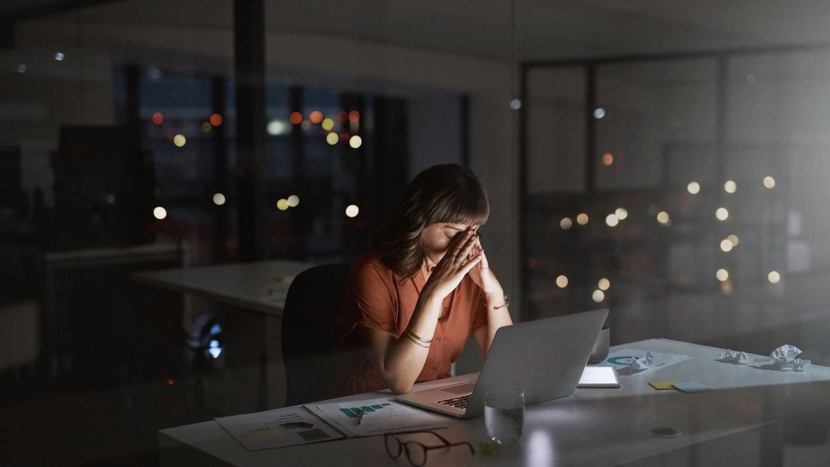 Stressed out female office worker sitting at her desk with her head in her hands