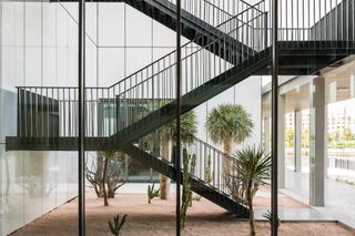 A black metal staircase leading from a central area with gravel and plants