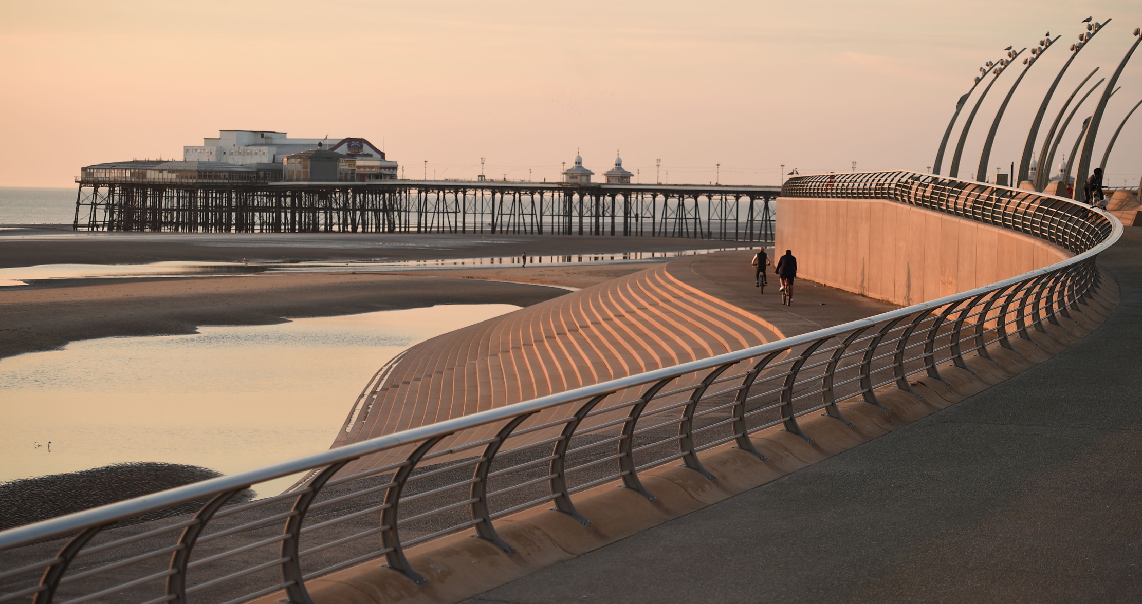 People cycle along the front toweards the north pier in the evening sunshine in Blackpool, north-west England.