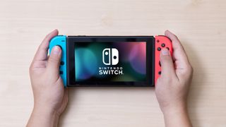Cómo activar el modo oscuro en Nintendo Switch - Hombre sosteniendo una Nintendo Switch