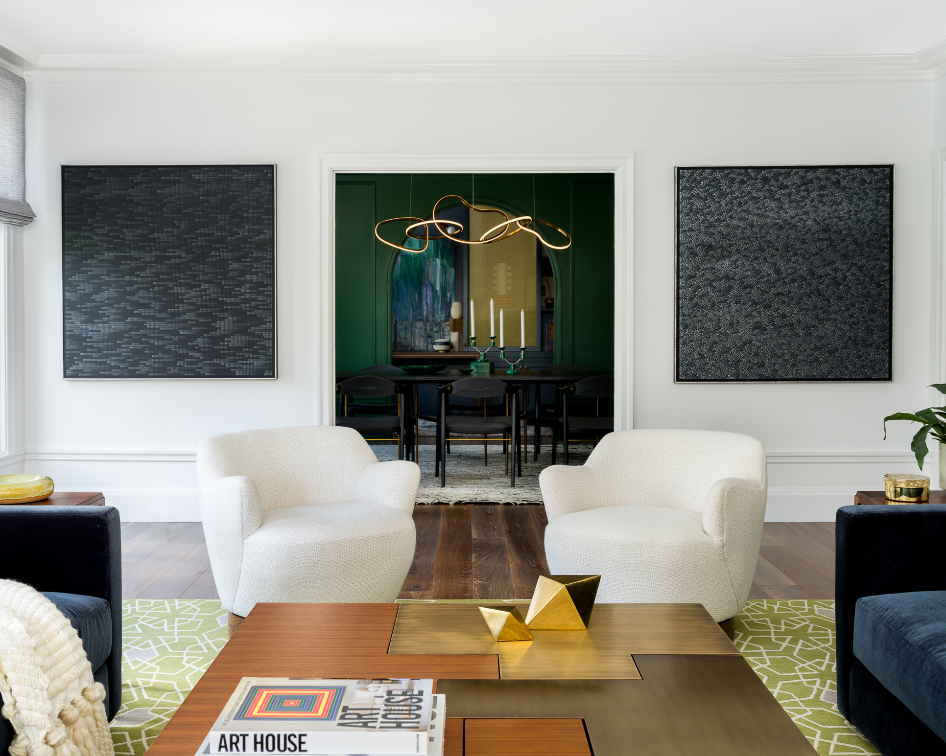 white living room with symmetrical art either side of the doorway and twin white chairs in front of each art piece