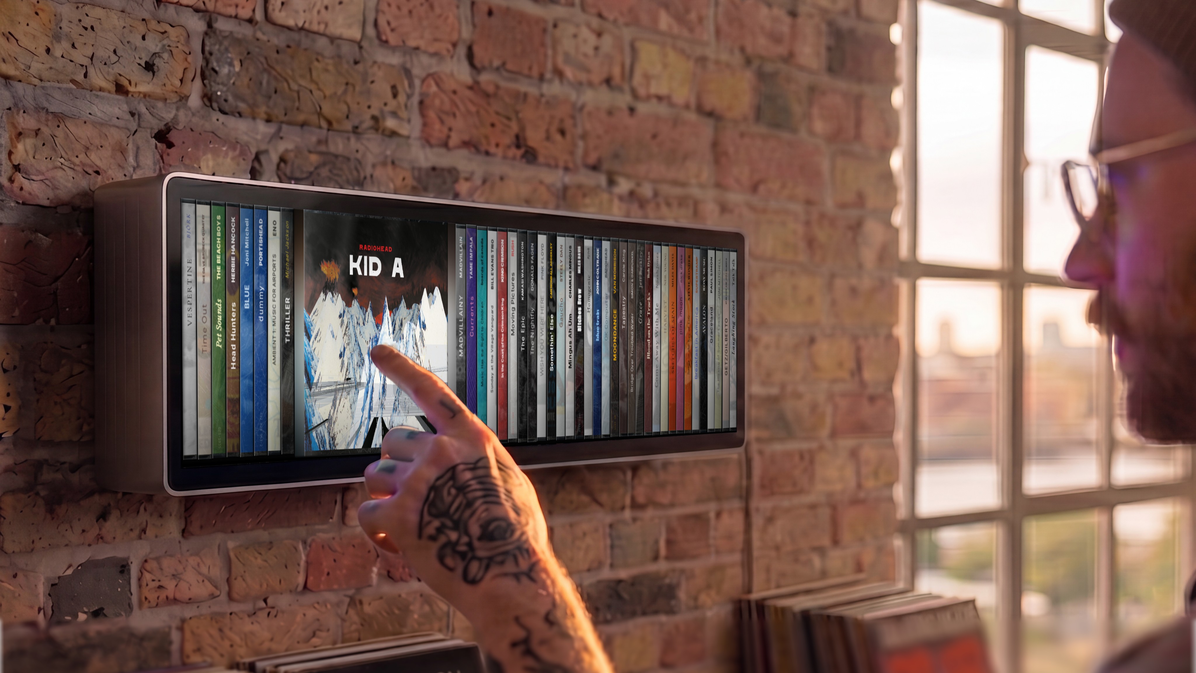 The Spine Music display mounted to a wall, with someone scrolling through their selection of albums