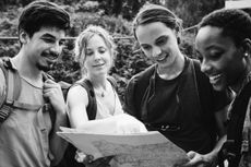 A group of friends looking at a map while hiking.