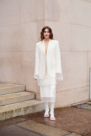 Guest wearing an all-white Sportmax sheer skirt and blazer set in Milan.