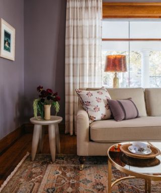 living room with purple walls, beige sofa and neutral patterned curtains