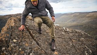 Man wearing Blundstone All Terrain boots and sliding down a rock