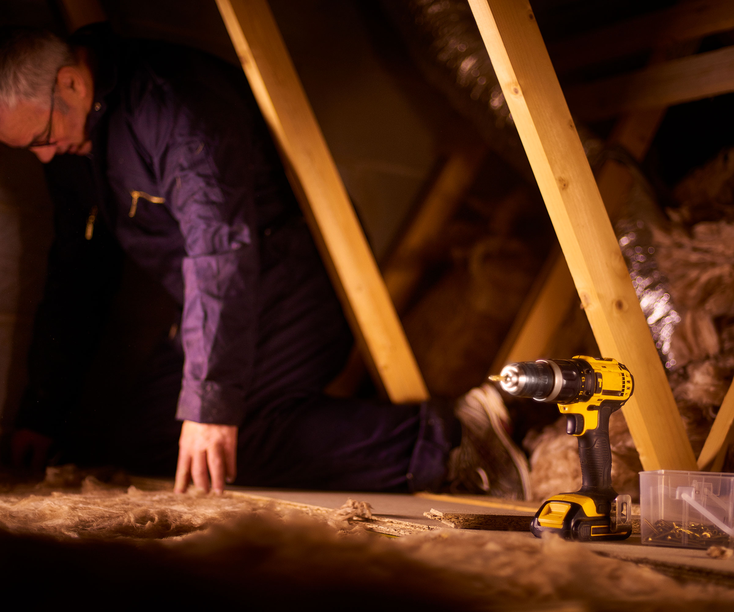 man in blue overalls installing loft insulation