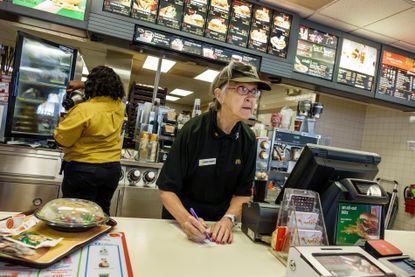 A senior woman working a fast food register.