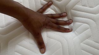 Tempur Hybrid Elite mattress with reviewer's hand on it