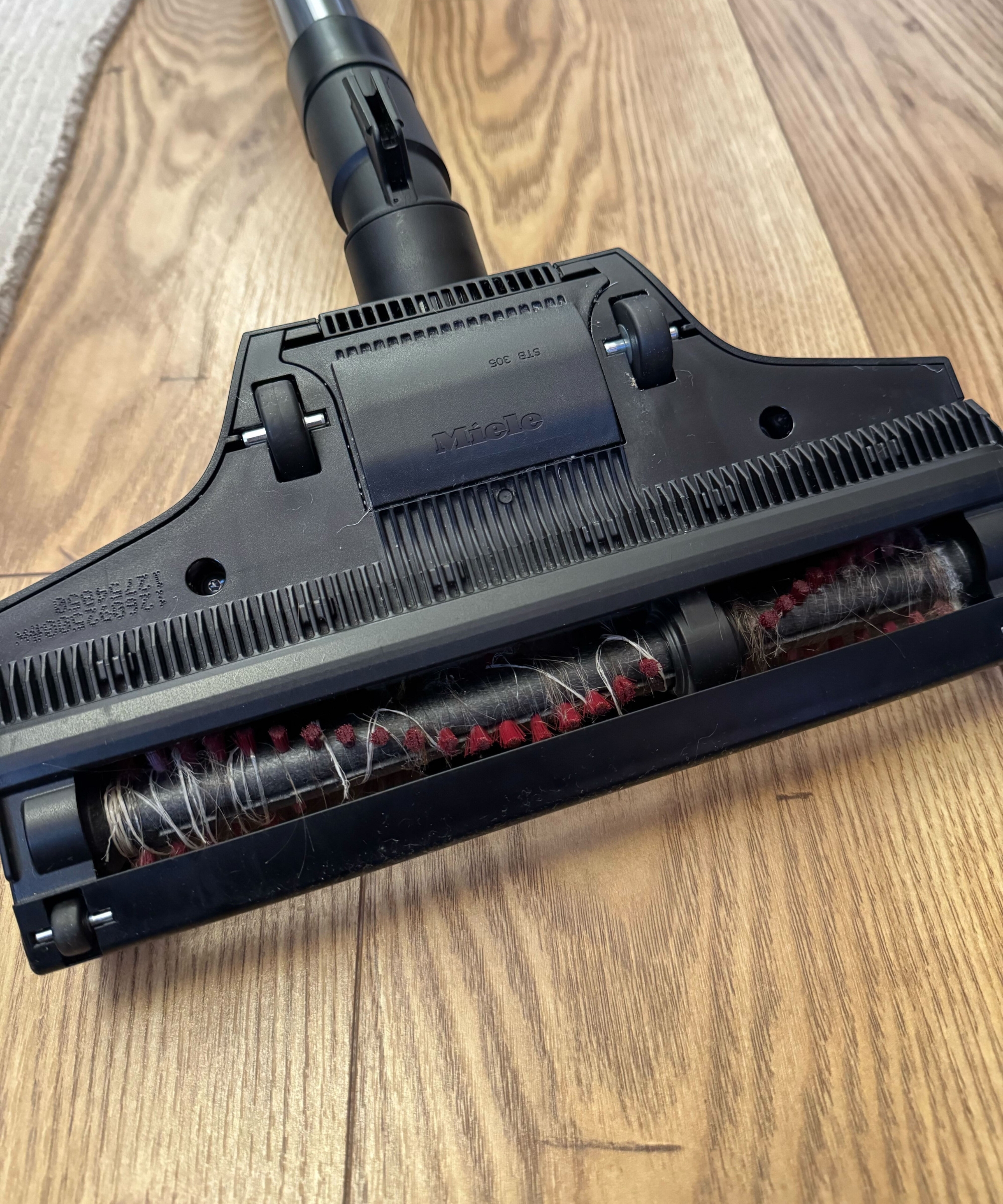 Miele Guard L1 Cat and Dog floorhead on wooden floor with hair and long plastic caught in brushroll.