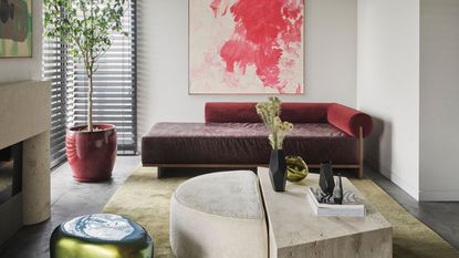 living room with gray walls, green rug, purple sofa, red artwork and travertine coffee table