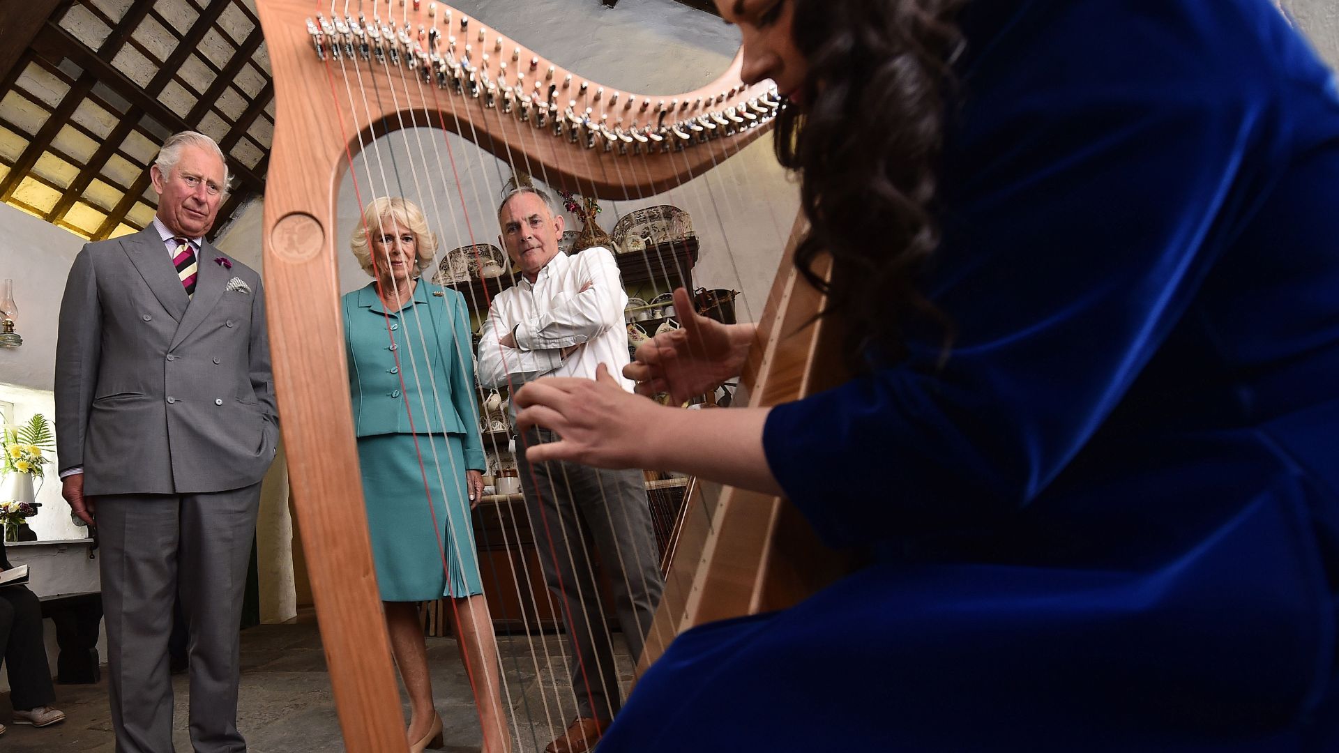 King Charles and Queen Camilla watch a harpist