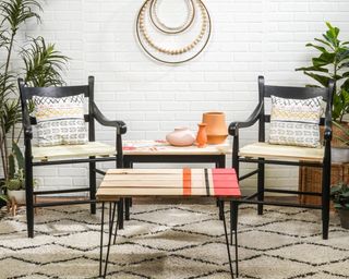 A pallet coffee table with metal hairpin legs and bright striped paint decor on Berber style rug with black wooden chairs in background