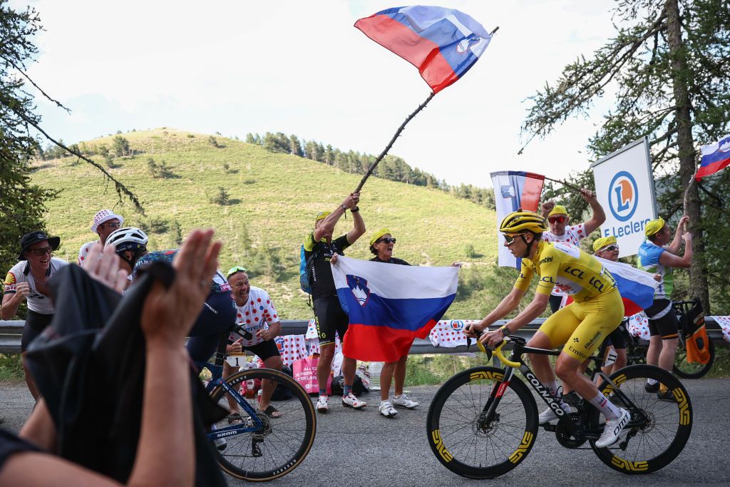 UAE Team Emirates team's Slovenian rider Tadej Pogacar wearing the overall leader's yellow jersey cycles past spectators waving Slovenian flags in the final ascent of the Col de la Couillole during the 20th stage of the 111th edition of the Tour de France cycling race, 132,8 km between Nice and Col de la Couillole, southeastern France, on July 20, 2024. (Photo by Anne-Christine POUJOULAT / AFP)