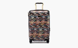 International Expandable 4-Wheeled Carry On luggage, by Tumi x Missoni. A hard shell case on wheels with a handle with a multi coloured zig zag pattern.
