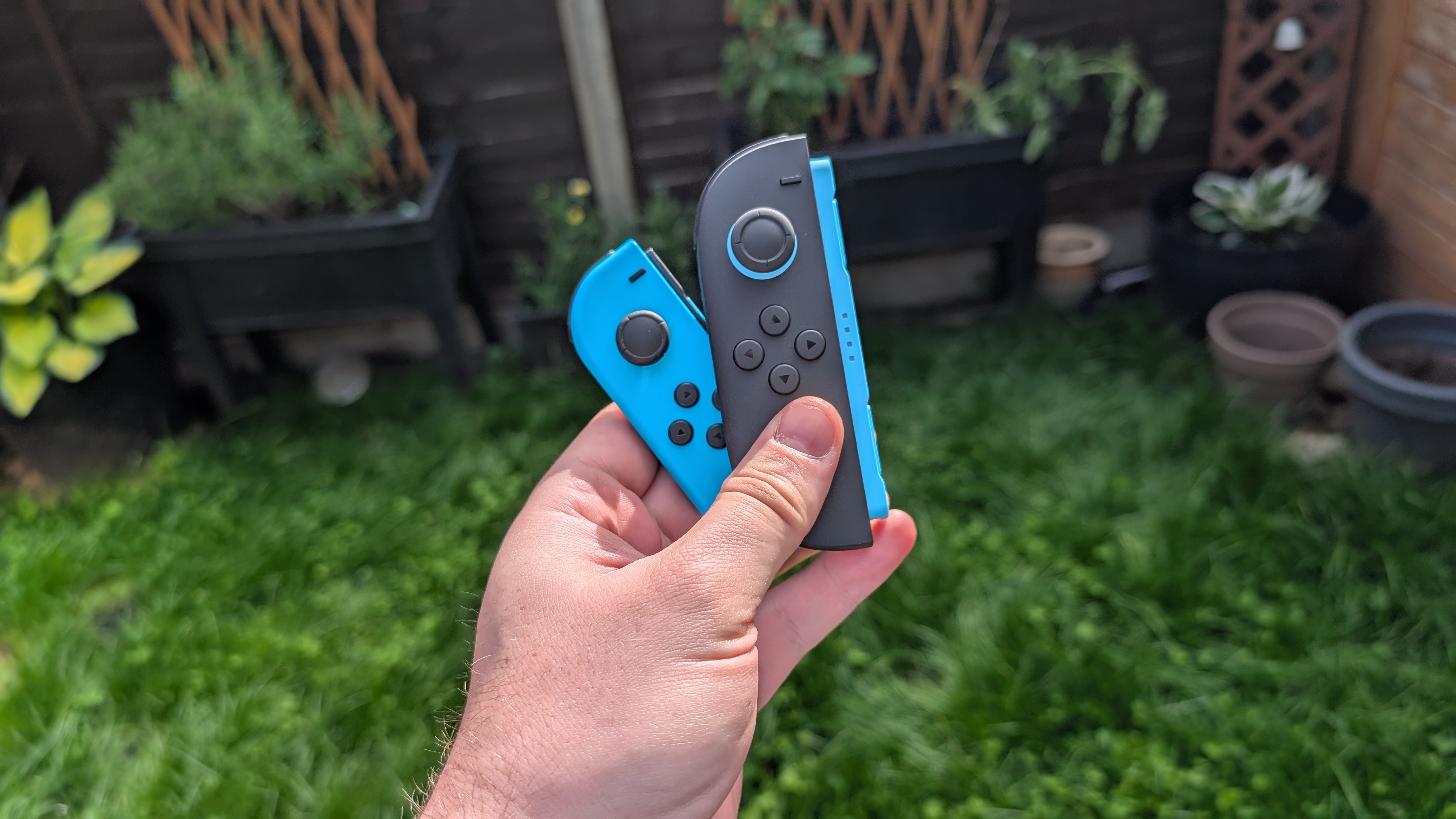 Nintendo switch joy-cons next to nintendo switch 2 joy-cons in the garden