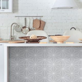 Kitchen with white brick walls and grey geometric tile stickers on island panel