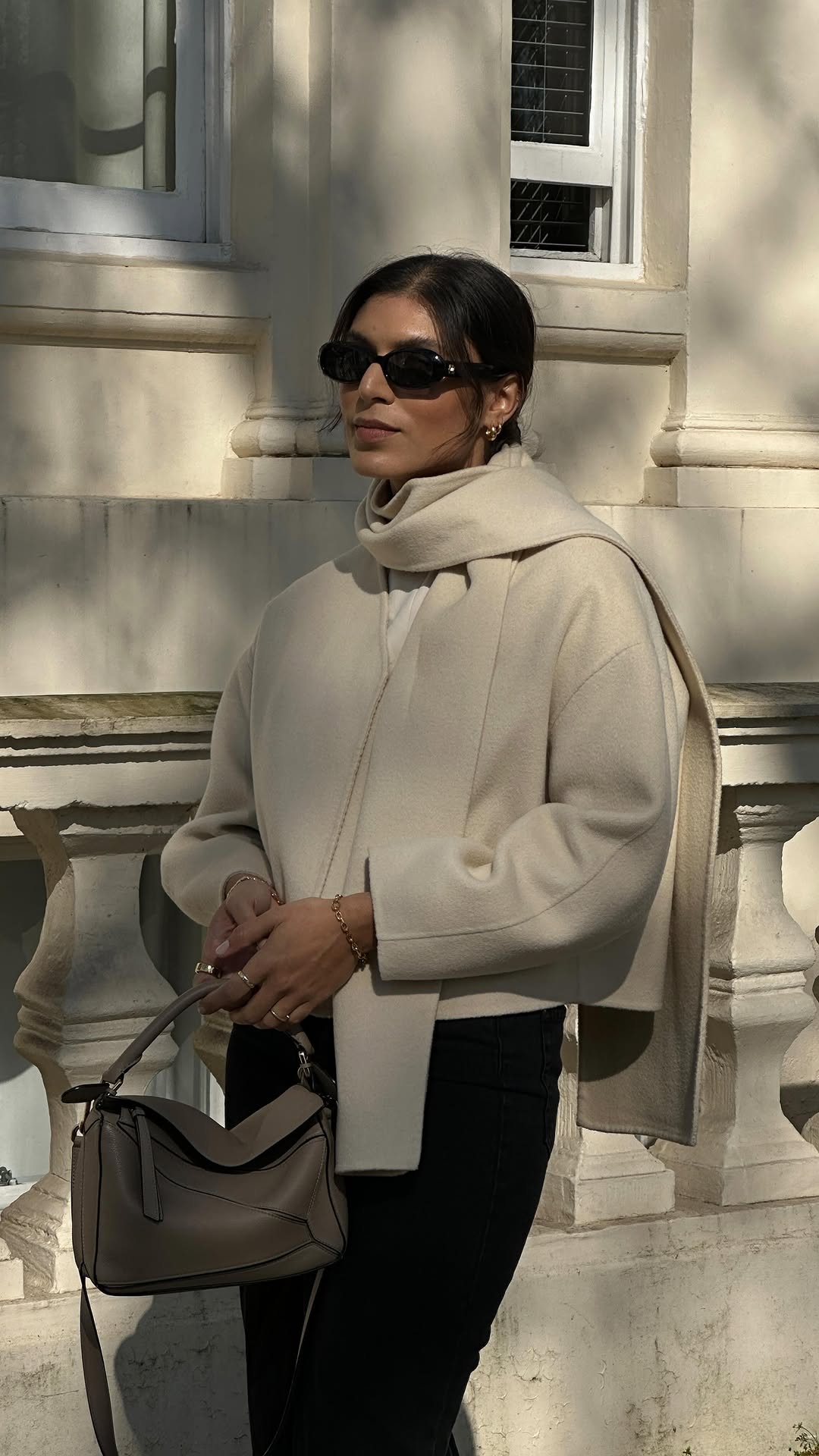 An image of @theindiaedit wearing a scarf jacket with leggings and a Loewe puzzle bag.