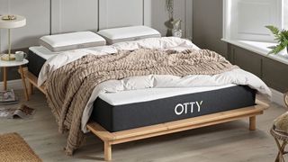 Otty Original Hybrid mattress in a gray stylish bedroom, with blankets on top