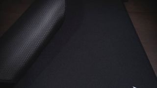 A Corsair MM Pro mouse pad on a desk being rolled up.