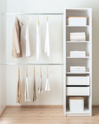 Clothes hanging neatly on a clothing rack on the left and shelves with towels and storage on the right
