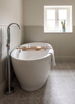 freestanding bath in bathroom with tongue and groove panelled walls and tiled floor