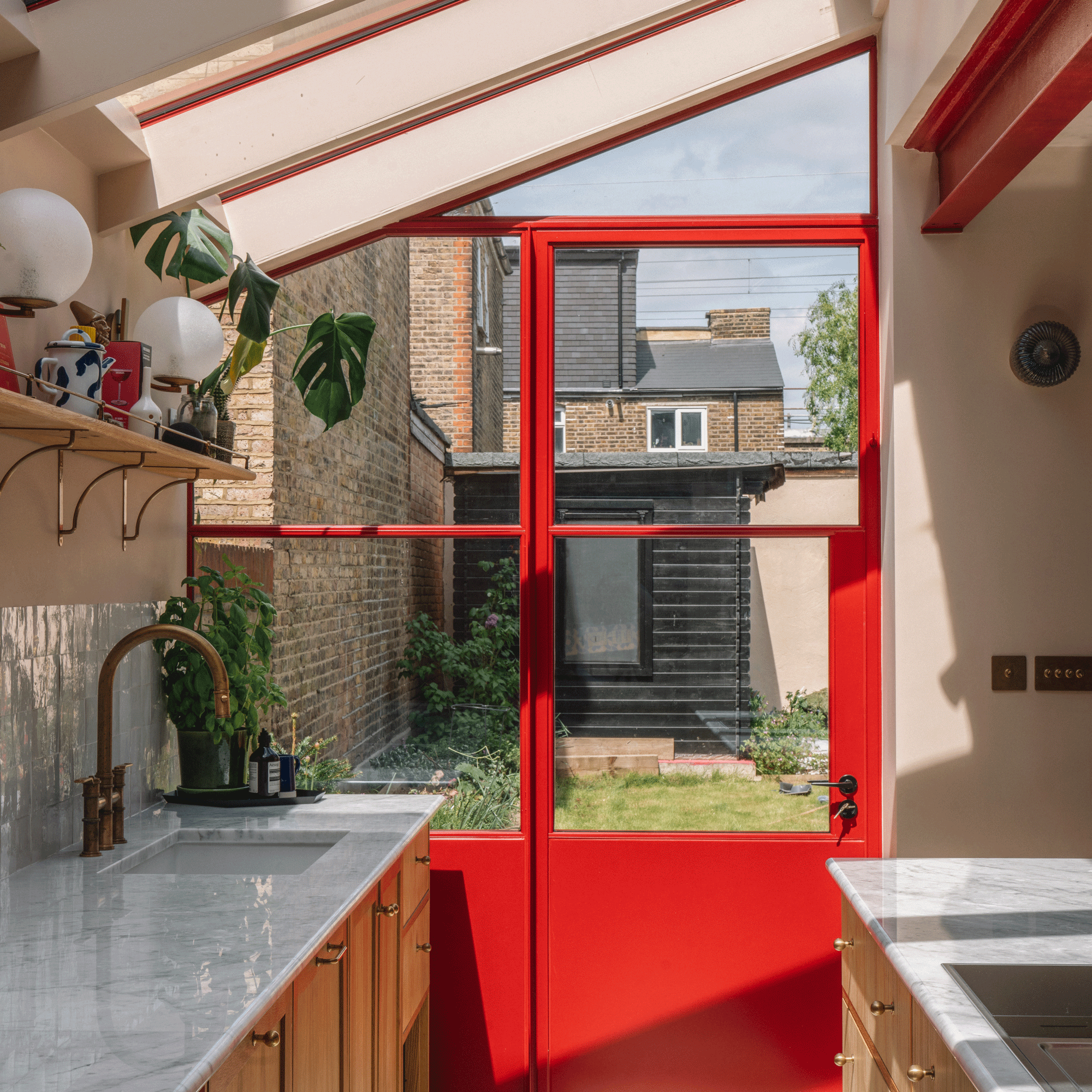 a side return extension kitchen with red patio doors skylight and marble countertops