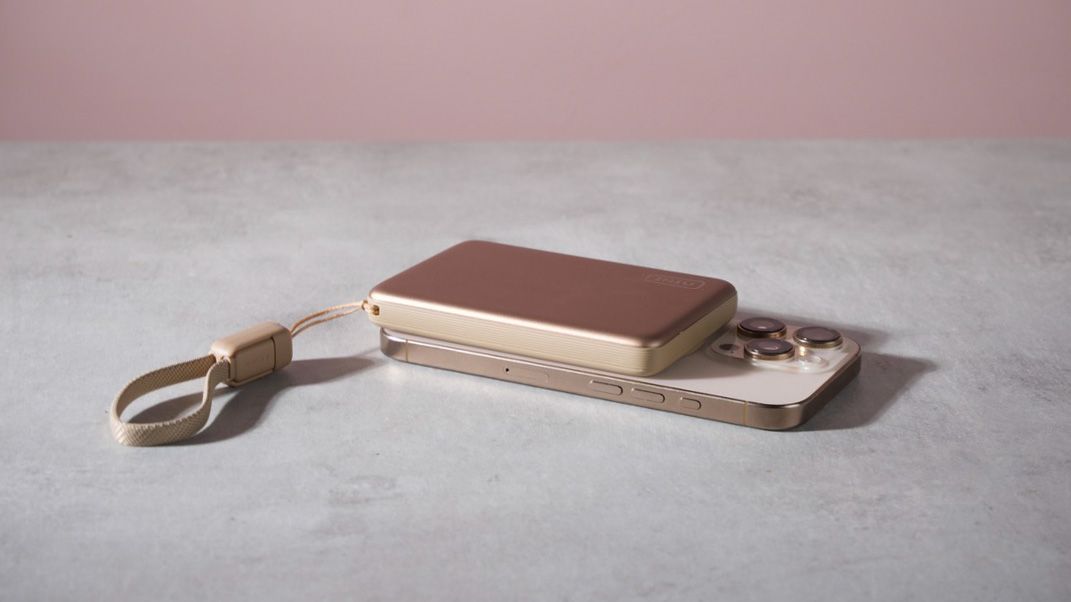 The Iniu SnapGo Air 10000mAh Power Bank attached to an iPhone 16 Pro laying flat on a table.