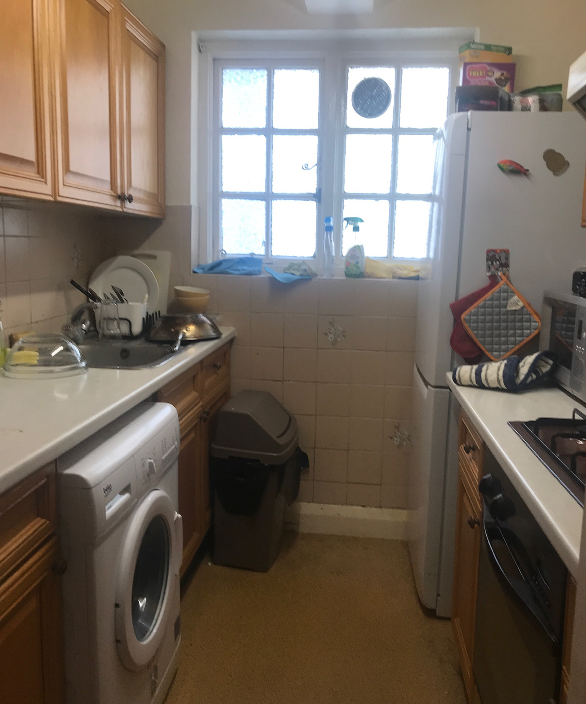 Before shot of a narrow galley kitchen, cramped with little light in need of makeover