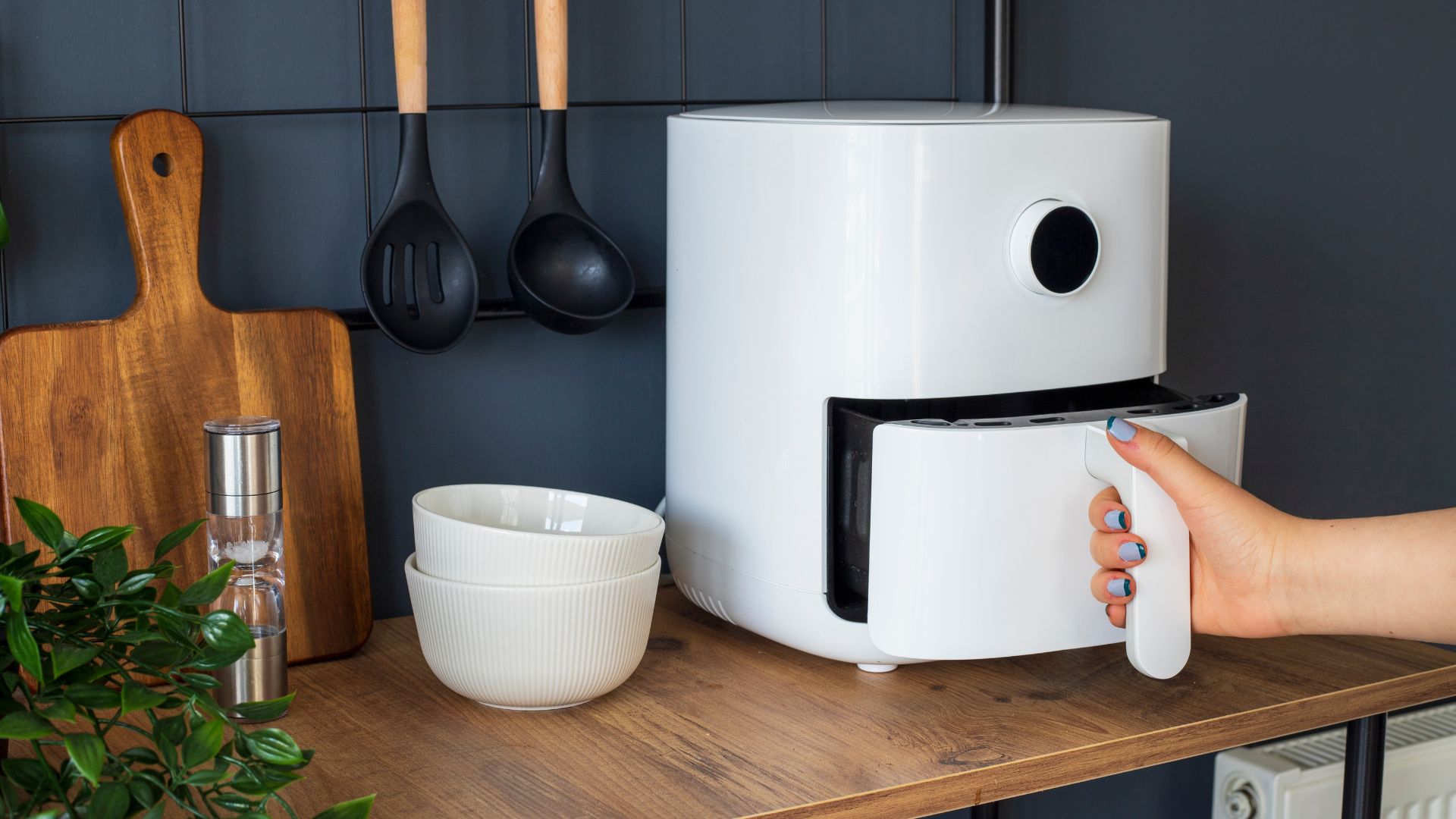 picture of woman opening air fryer in kitchen