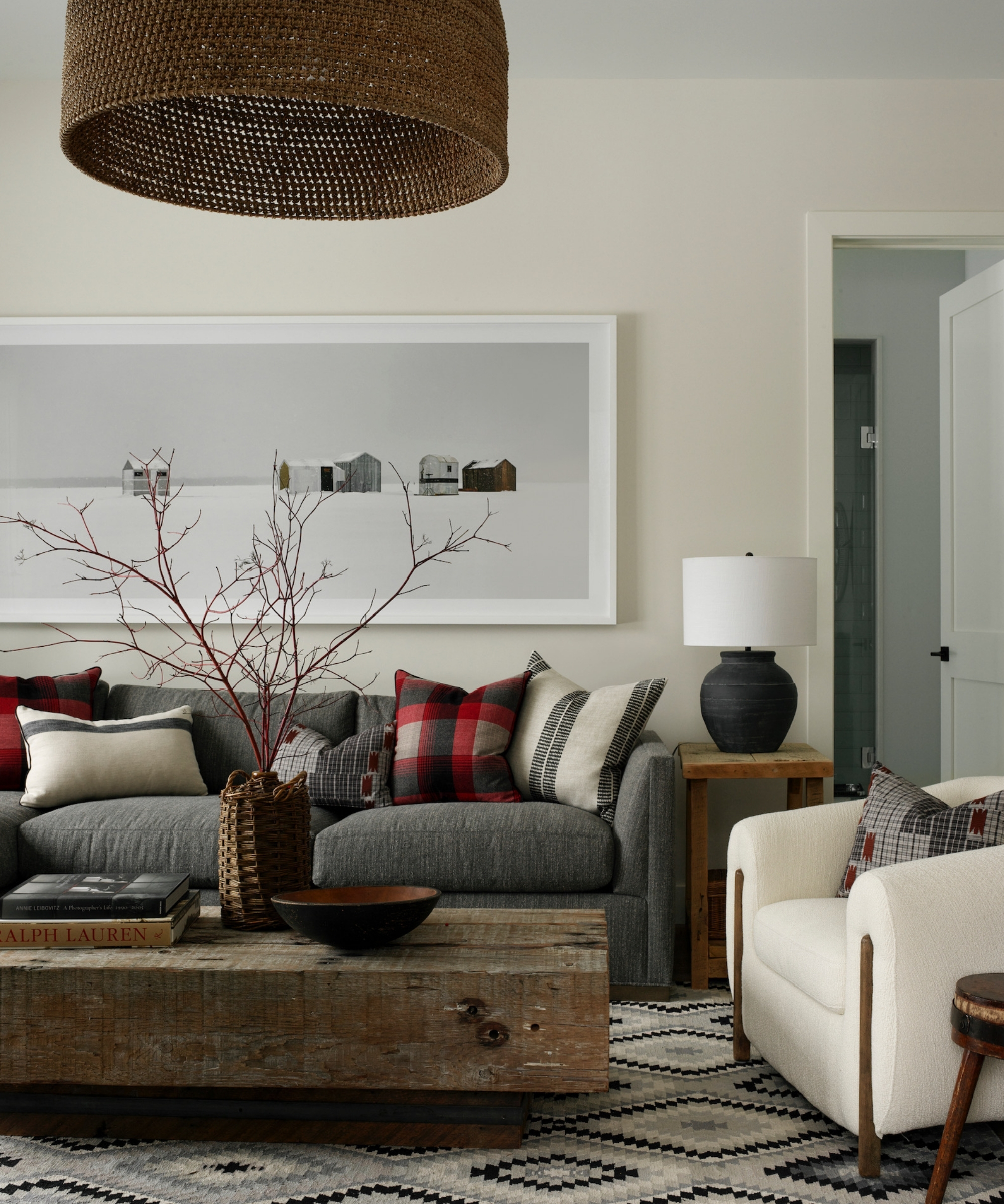 Living room with gray sofa, white armchair, rustic wood coffee table, side tables and layered patterned pillows.