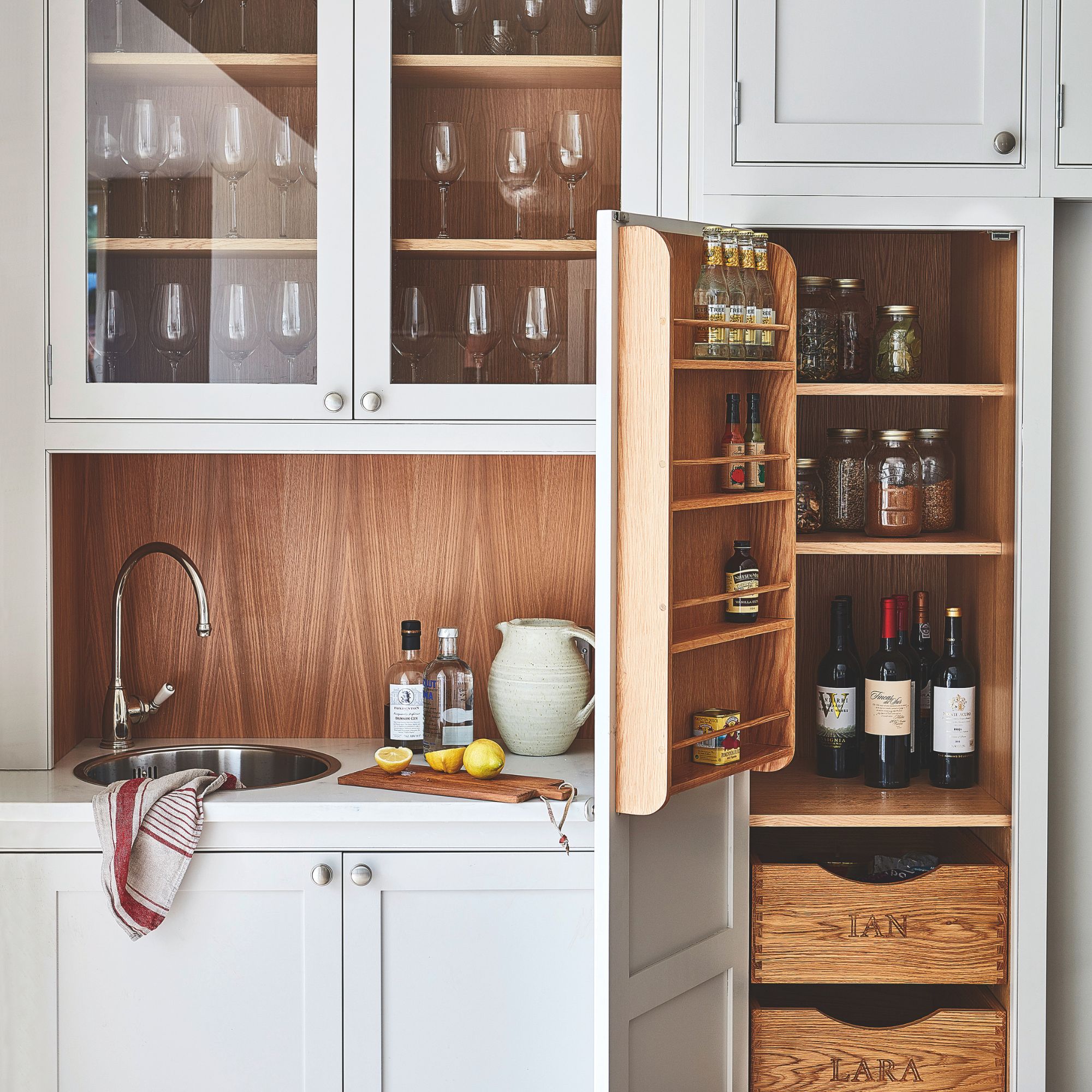 Grey kitchen cupboards, with one of them open and showing the storage inside