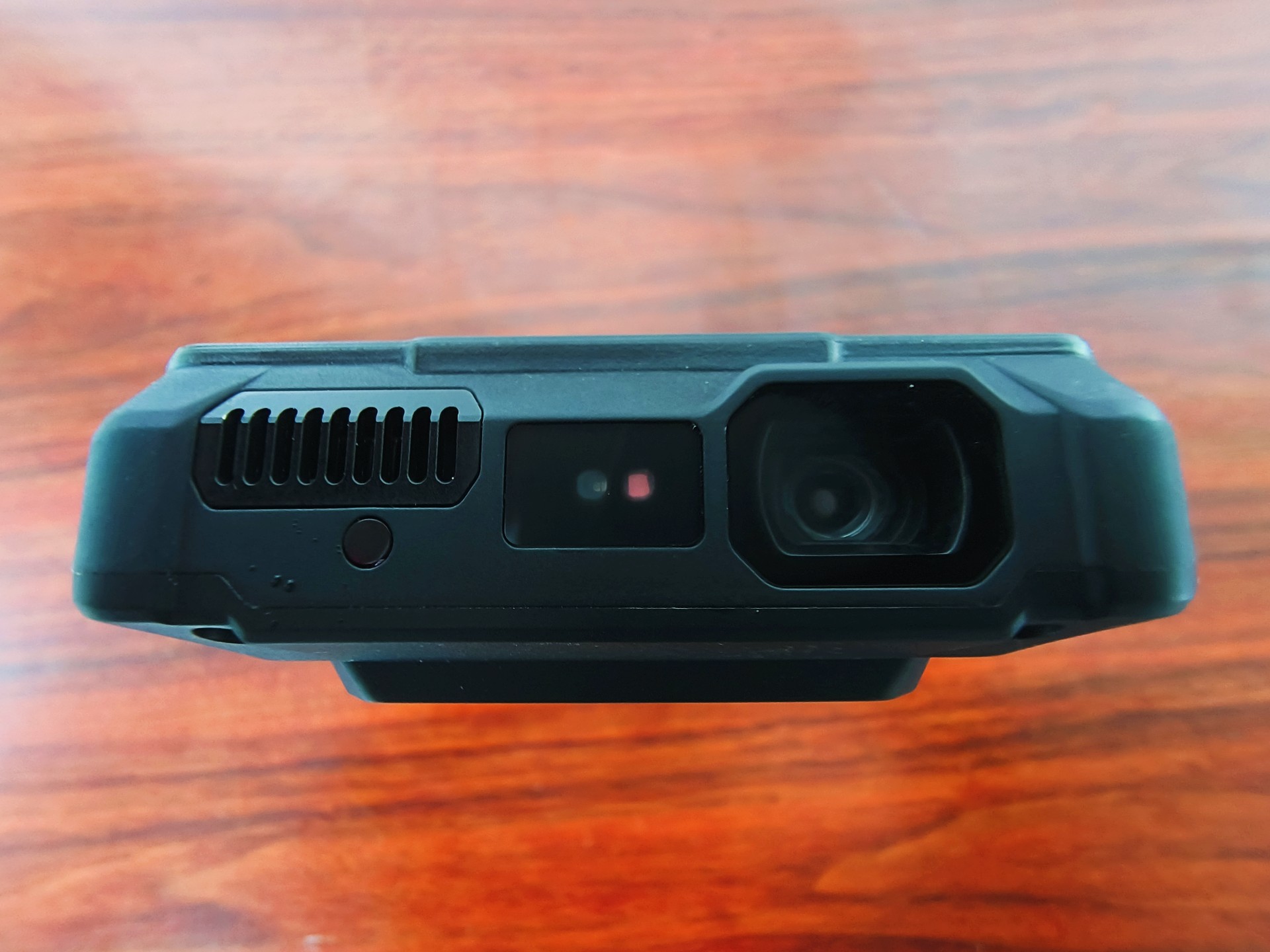 The top edge of the rugged smartphone features a large projector lens assembly, a sensor, and a ventilation grill.
