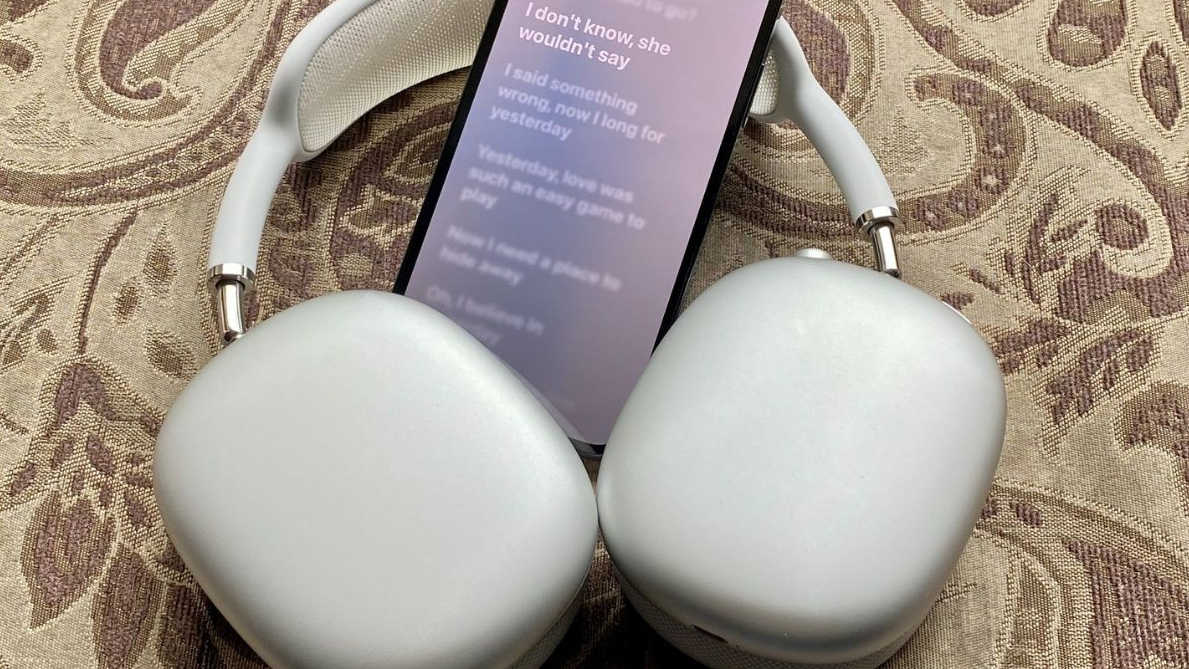 AirPods Max dengan iPhone memainkan Apple Music di sebelahnya.