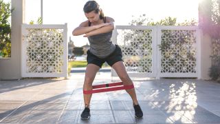 Woman warms up with resistance band crab walk movement
