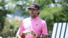 Bubba Watson - wearing his classic pink polo and a black RangeGoats cap - looks on during LIV Golf Nashville in 2024