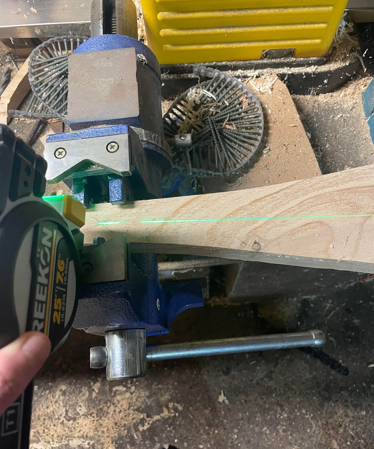 A side on view of a laser tape measure measuring the middle of a block of wood