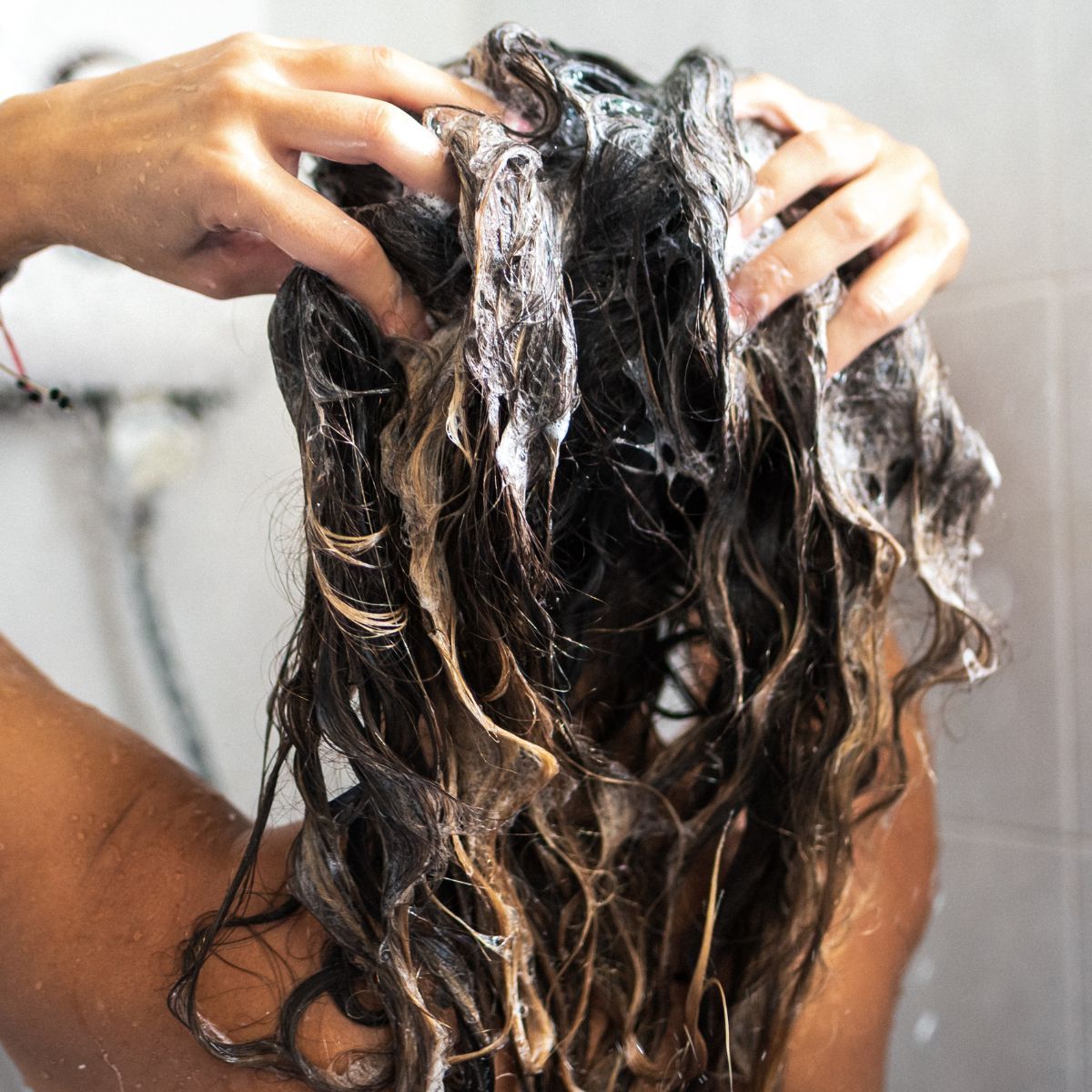 woman facing away from the camera in the shower washing her hair - best drugstore shampoo