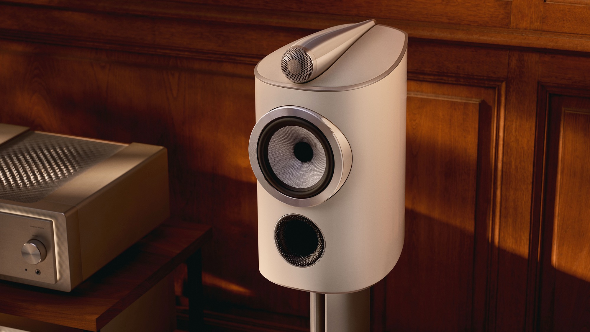 A white Bowers &amp;amp; Wilkins 805 D5 standmount speaker on its stand in front of a wood-panelled wall.
