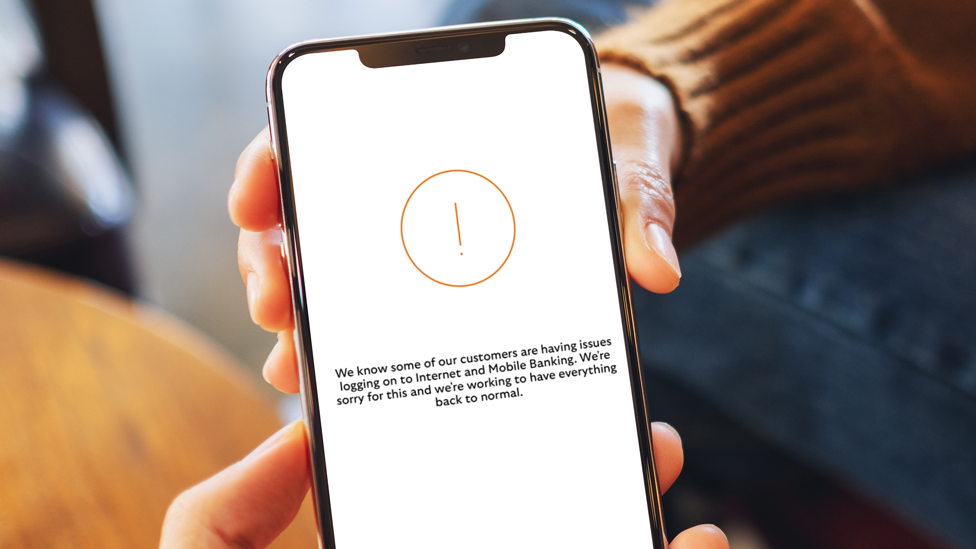 A hand holding a phone showing a Lloyds Bank error message