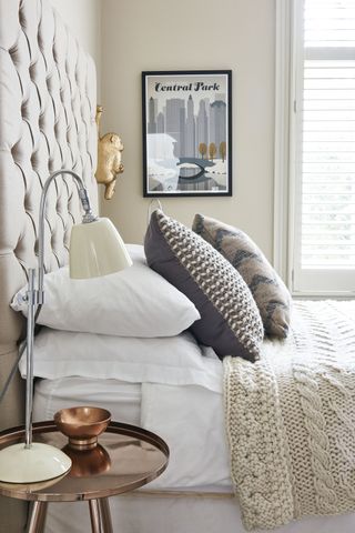 neutral bedroom with button back headboard, knitted throw and cushions
