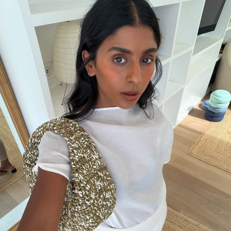 Monikh wears a white tee and a green and white khaite bag.