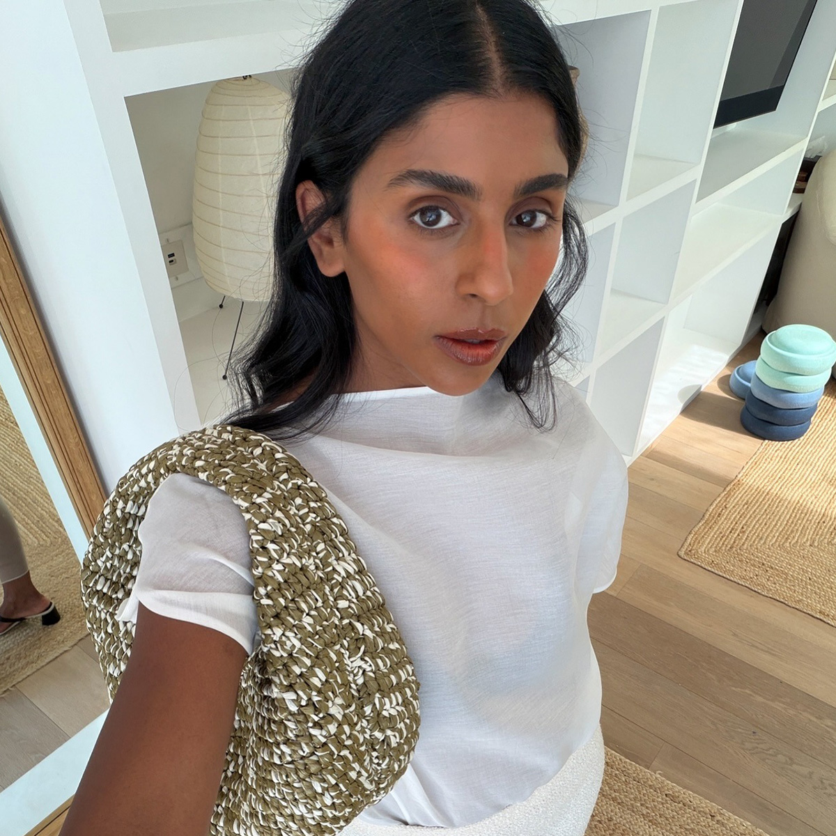 Monikh wears a white tee and a green and white khaite bag.