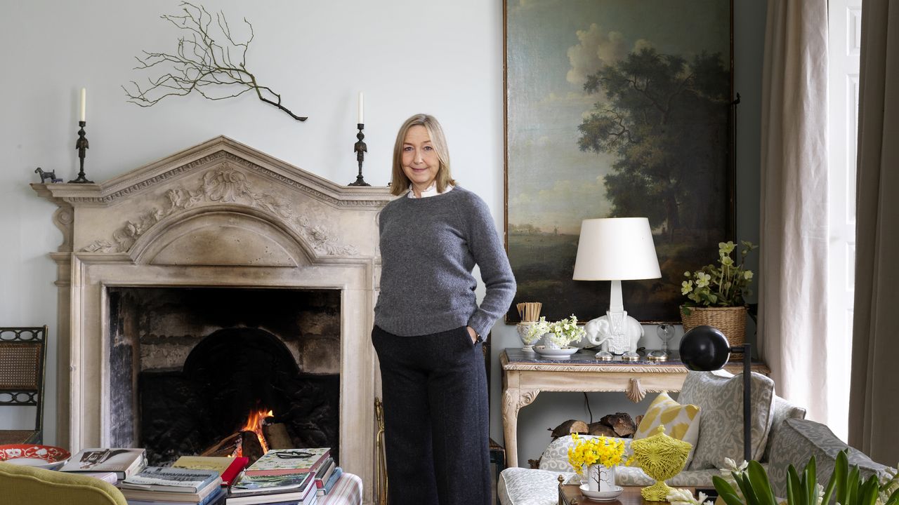 Cath Kidston by fireplace in living room of family home in Cotswolds