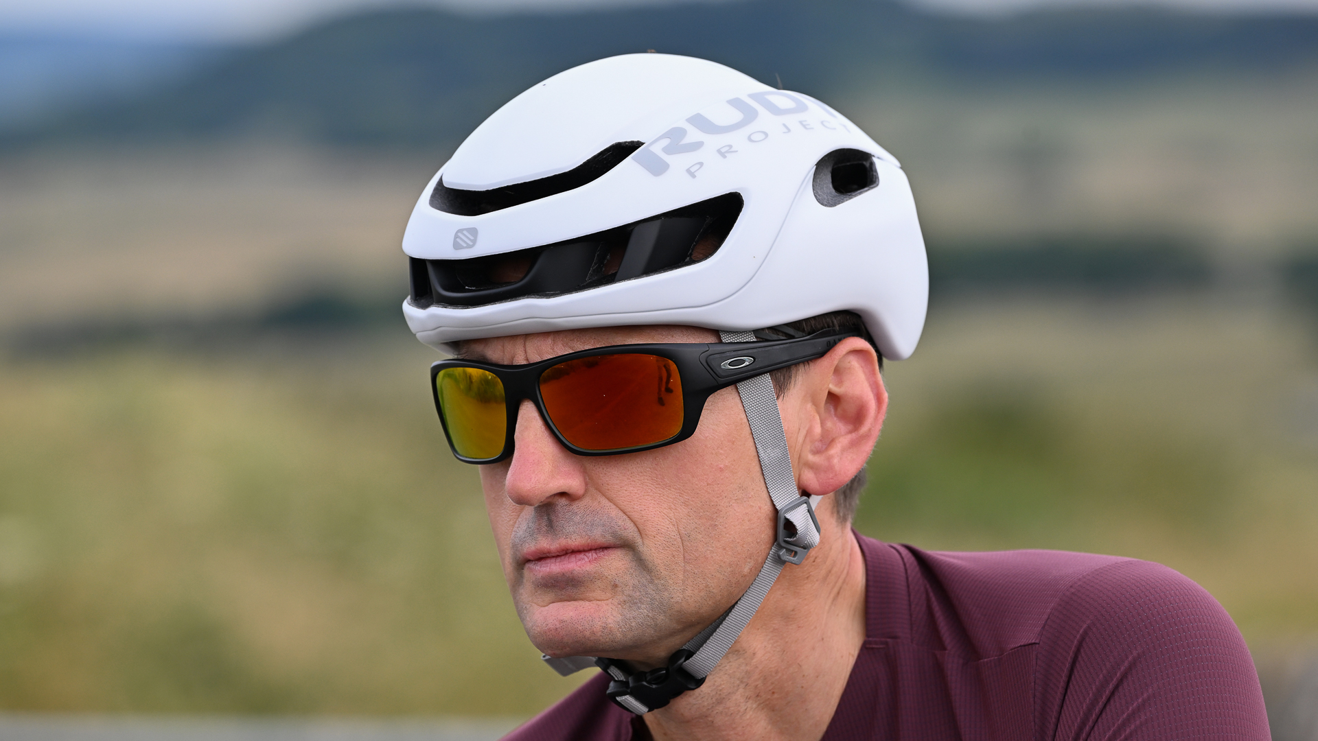 close up of man wearing a white cycling helmet and sunglasses