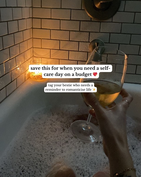 A dark, candlelit bubble bath with someone holding a glass of wine, with the text 'Save this for when you need a self care day on a budget'