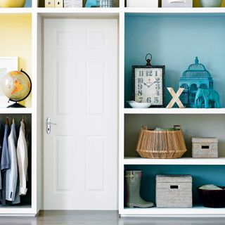Open shelving built around a white internal door and painted in pastel shades