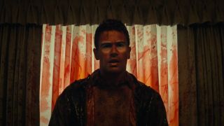 theo james covered in blood stnading by a window with the blinds closed in the movie the monkey