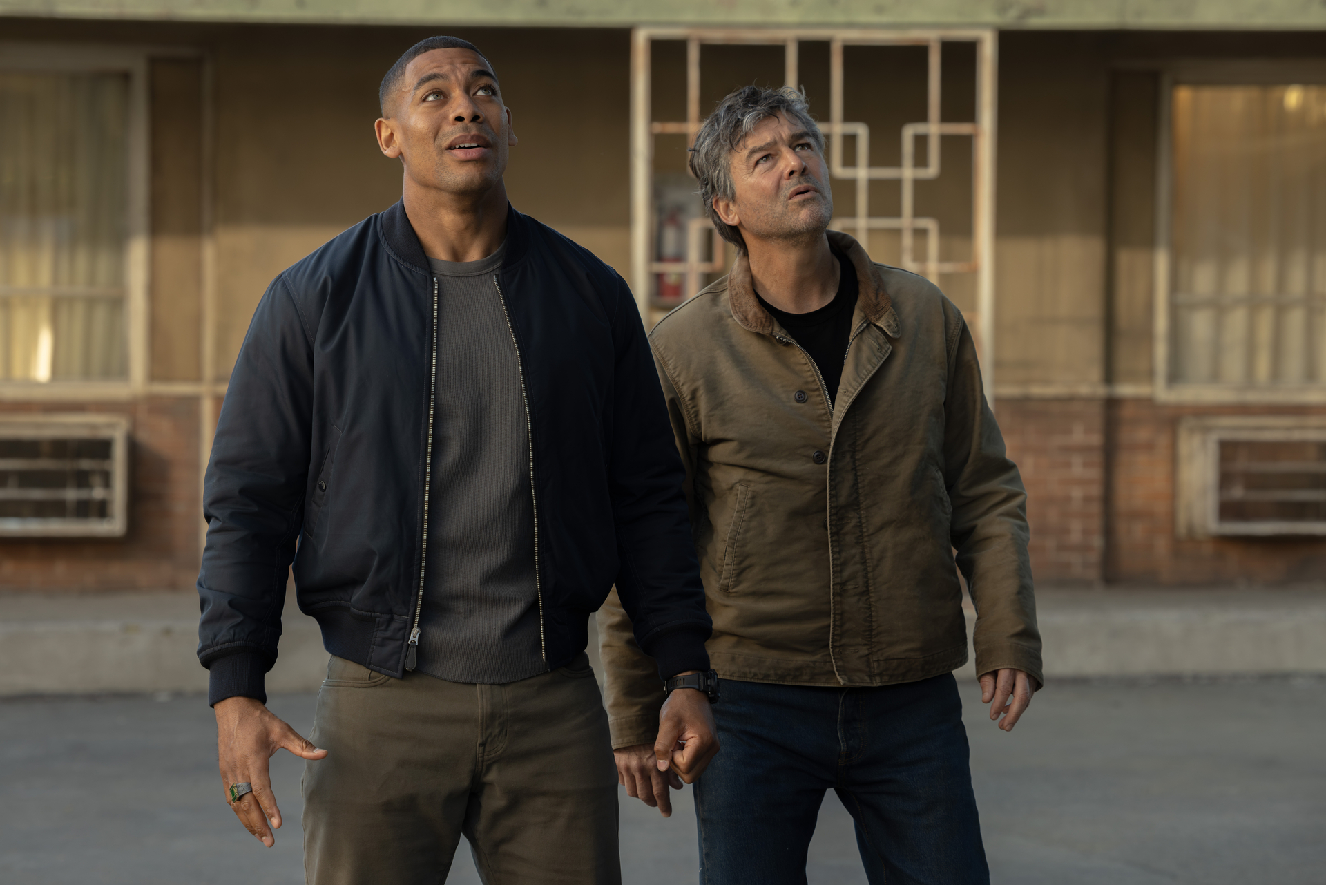 John and Hal standing in motel parking lot looking up to the sky in Lanterns Episode 2